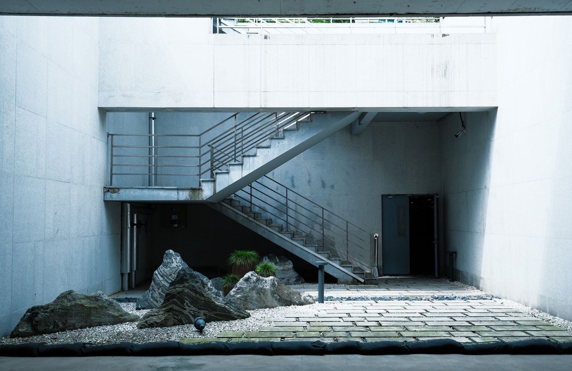 Escadaria de betão e jardim de pedra num pátio minimalista
