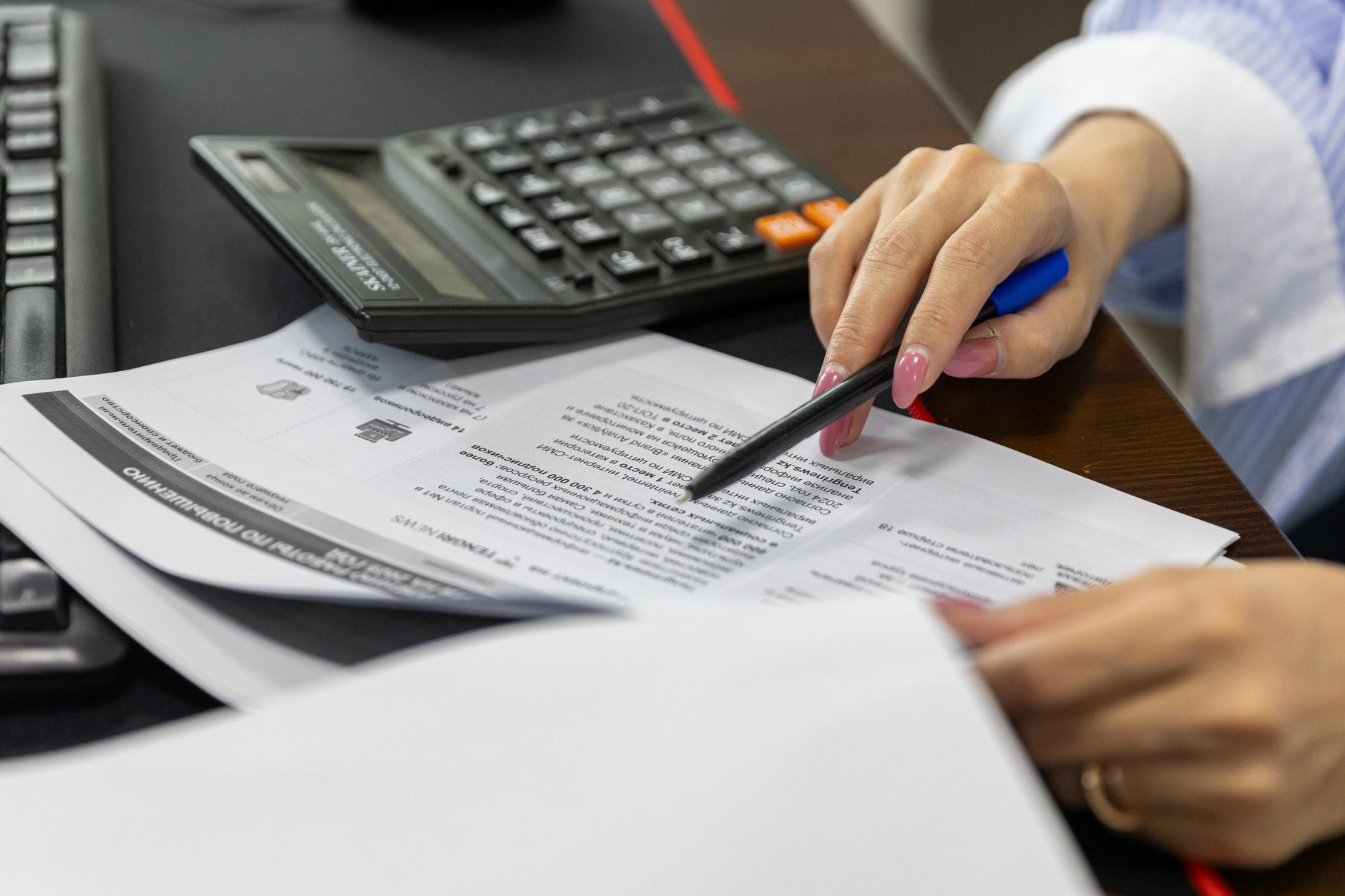Revisão de mapas financeiros com calculadora sobre a secretária